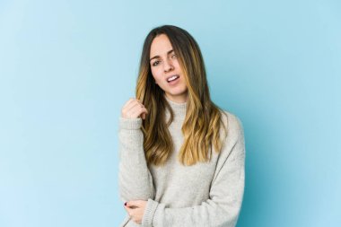 Beyaz bir kadın mavi arka planda izole edilmiş dirsek masajı yapıyor, kötü bir hareketin ardından acı çekiyor..