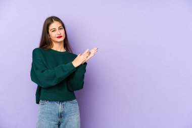 Mor arka planda izole edilmiş genç beyaz kadın enerjik ve rahat hissediyor, ellerini ovuşturuyor..