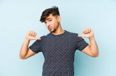 Mavi arka planda izole edilmiş genç bir Arap gururlu ve kendinden emin hissediyor, örnek olarak..