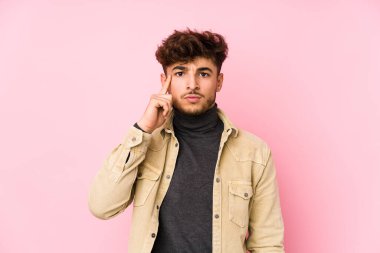 Arka planda poz veren genç bir Arap adam, bir göreve odaklanmış, parmağıyla tapınağı işaret ediyor..