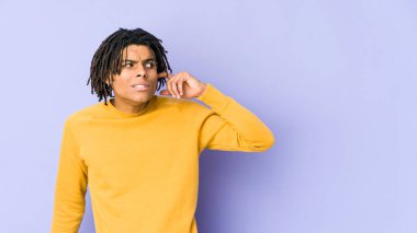 Rasta saç stili giyen genç siyah adam kulaklarını elleriyle kapatıyor..