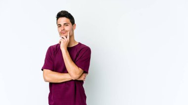 Beyaz arka planda soyutlanmış genç beyaz bir adam düşünüyor ve yukarı bakıyor, yansıtıyor, düşünüyor, hayal kuruyor..