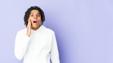 Genç Afrikalı Amerikalı Rasta adam yüksek sesle bağırıyor, gözleri açık ve elleri gergin tutuyor..