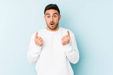 Mavi arka planda izole edilmiş beyaz bir adam ağzı açık bir şekilde üst tarafı işaret ediyor..
