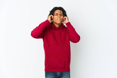 Genç Afrikalı Amerikalı Rasta adam kulaklarını parmaklarıyla kapatıyor, gürültülü bir ortam yüzünden stresli ve çaresiz..