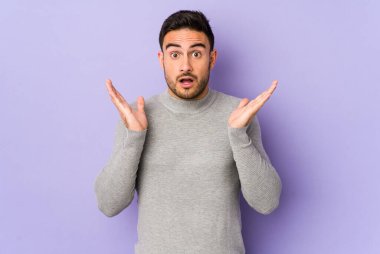 Mor arka planda izole genç beyaz adam şaşırdı ve şok oldu..