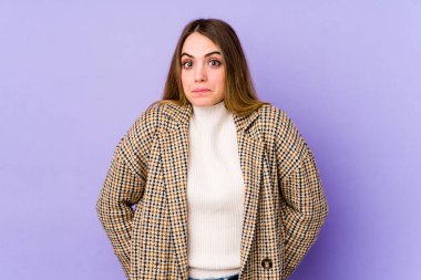 Mor arka planda soyutlanmış beyaz bir kadın omuzlarını silker ve gözleri açık kalır..