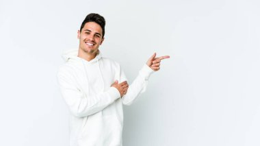 Beyaz arka planda izole edilmiş genç beyaz adam işaret parmağıyla işaret ederek gülümsüyor..