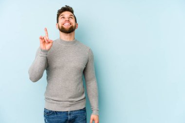 Mavi arka planda izole genç beyaz adam işaret iki ön parmakları boş bir boşluk gösteren.