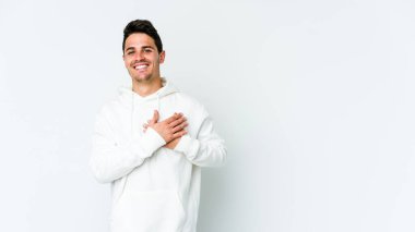 Beyaz arka planda izole edilmiş beyaz tenli genç bir adam, dostane bir ifadeye sahip, avuçlarını göğsüne bastırıyor. Aşk konsepti.