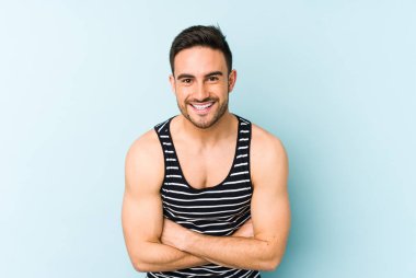 Kafkasyalı genç adam mavi arka planda izole edilmiş gülüyor ve eğleniyor..
