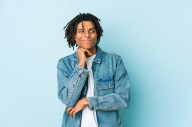 Kot ceket giyen genç siyahi bir adam şüpheli ve şüpheci bir ifadeyle yana bakıyor..