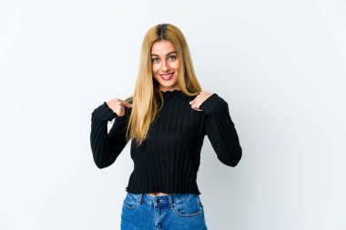 Beyaz arka planda izole edilmiş genç sarışın kadın parmağını göstererek şaşırdı, geniş bir gülümsemeyle..