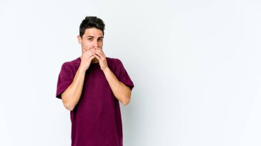 Beyaz arka planda izole edilmiş genç beyaz bir adam ağzı kapalı ve elleri endişeli görünüyor..