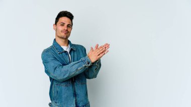 Beyaz arka planda izole olmuş genç beyaz bir adam enerjik ve rahat hissediyor, ellerini ovuşturuyor..