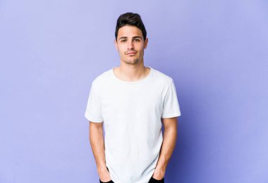 Mor arka planda izole edilmiş genç beyaz adam üzgün, ciddi yüz, sefil ve hoşnutsuz hissediyor.