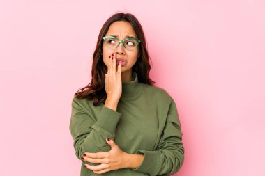 Genç, Latin kökenli bir kadın kendini izole etmiş esniyor. Ağzıyla ağzını kapatan yorgun bir hareket sergiliyor..