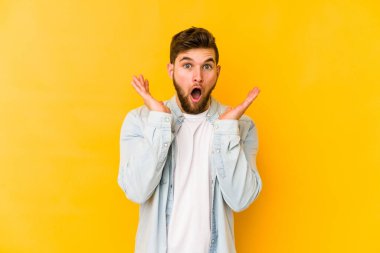 Sarı arka planda izole edilmiş genç beyaz adam şaşırdı ve şok oldu..