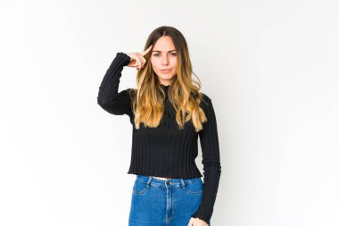 Beyaz arka planda izole edilmiş beyaz tenli genç bir kadın şakağı parmağıyla işaret ediyor, düşünüyor ve bir göreve odaklanıyor..