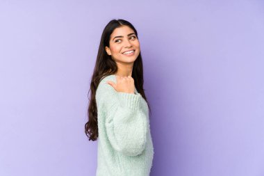 Mor arka planda izole edilmiş genç Hintli kadın başparmak uzakta, gülüyor ve kaygısız.