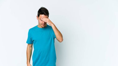 Beyaz arka planda izole olmuş genç beyaz bir adam başı ağrıyor, yüzüne dokunuyor..