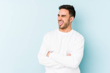 Kafkasyalı genç adam mavi arka planda izole edilmiş komik ve dost canlısı bir dil uzatıyor..