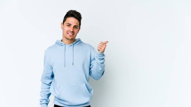 Beyaz arka planda izole edilmiş genç beyaz bir adam işaret parmağıyla fotokopi alanını işaret ederek şok oldu..