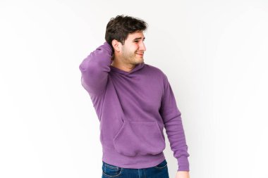 Genç adam beyaz arka planda izole edilmiş. Çok yorgun ve uykulu. Elini başının üstünde tutuyor..