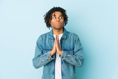 Kotlu ceket giyen genç siyahi bir adam el ele tutuşup, ağzının kenarında dua ediyor, kendinden emin hissediyor..