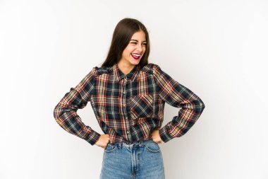 Beyaz arka planda izole genç beyaz kadın mutlu bir şekilde gülüyor ve ellerini karnının üstünde tutarak eğleniyor..