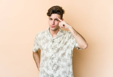 Beyazların arka planında izole edilmiş genç beyaz bir adam şakağı parmağıyla işaret ediyor, düşünüyor ve bir göreve odaklanıyor..