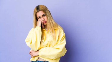 Mor arka planda soyutlanmış genç sarışın kadın üzgün ve dalgın hissediyor..