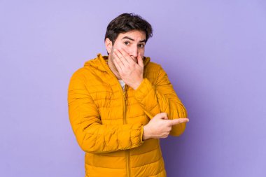 Mor arka planda izole genç adam yan tarafı işaret ediyor.