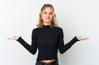 Beyaz arka plandaki genç beyaz kadın kollarıyla ölçek yapıyor, mutlu ve kendinden emin hissediyor..