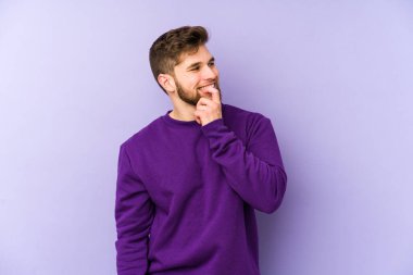 Mor arka planda izole edilmiş genç beyaz adam rahatlamış bir şeyin fotokopi odasına baktığını düşünüyor..