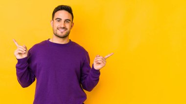 Sarı fırında izole edilmiş genç beyaz adam farklı kopya alanlarını gösteriyor, birini seçiyor, parmaklarıyla gösteriyor..