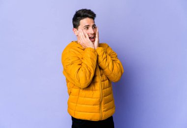 Mor arka planda izole edilmiş genç beyaz adam korkmuş ve korkmuş..