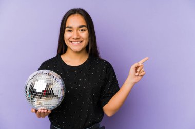 Genç Asyalı bir kadın, izole edilmiş bir balo düzenliyor. Gülümsüyor ve işaret ediyor. Boş alanda bir şey gösteriyor..