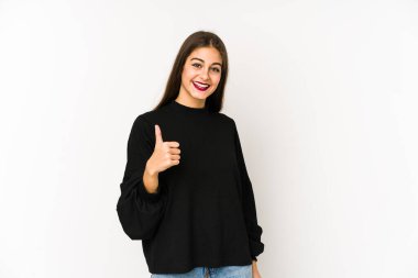 Beyaz arka planda izole edilmiş genç beyaz kadın gülümsüyor ve başparmağını kaldırıyor.