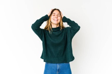 Beyaz arka planda soyutlanmış beyaz bir kadın ellerini başının üstünde tutarak neşeyle gülüyor. Mutluluk kavramı.