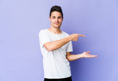 Mor arka planda izole edilmiş genç beyaz bir adam, elinde bir fotokopi alanı tutarken heyecanlanıyor..