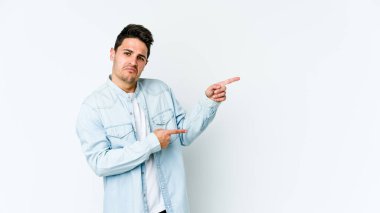 Beyaz arka planda izole edilmiş genç beyaz bir adam işaret parmağıyla fotokopi alanını işaret ederek şok oldu..