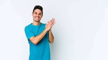 Beyaz arka planda izole olmuş genç beyaz bir adam enerjik ve rahat hissediyor, ellerini ovuşturuyor..