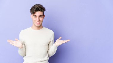 Mor arka planda izole genç beyaz adam kollarıyla ölçek yapar, mutlu ve kendinden emin hisseder..