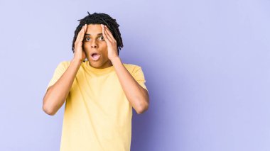 Genç Afrikalı Amerikalı Rasta adam yüzünün yarısını palmiye ile örterek eğleniyor..