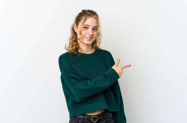 Beyaz arka planda genç beyaz bir kadın gülümsüyor ve boş uzayda bir şeyler gösteriyor..