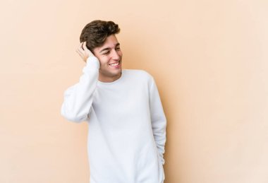 Beyazlı genç adam bej arka planda izole edilmiş zafer, tutku ve coşkuyu kutluyor, mutlu bir ifade..