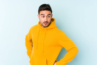 Mavi arka planda soyutlanmış genç beyaz bir adam gülümsüyor, neşeli ve keyifli görünüyor..