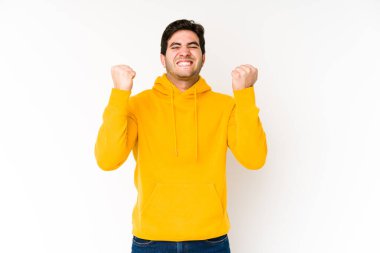 Genç adam beyaz arka planda yalnız başına tasasız ve heyecanlı tezahürat yapıyor. Zafer konsepti.