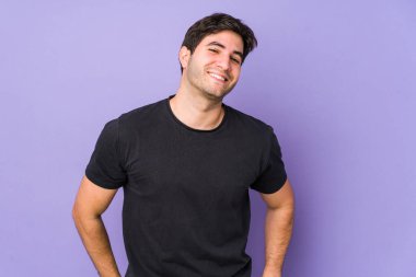 Mor arka planda izole edilmiş genç adam mutlu, güler yüzlü ve neşeli.